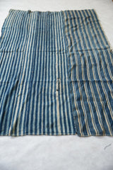 Hand-woven African indigo textile with blue and natural stripes, showing visible panel seams.