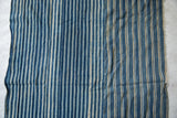 Vintage African indigo textile close-up, showing handwoven blue and ecru stripes with seams.