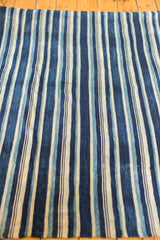Vintage hand woven indigo textile featuring nuanced blue stripes and textured cotton.
