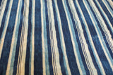 Indigo blue striped hand-woven textile with varying dye shades and visible vintage texture.