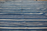 Textured vintage handwoven indigo blue textile, showing varied stripe widths and tones.