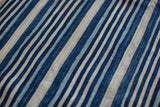 Close-up of vintage African indigo textile showcasing hand-woven texture and varied blue stripes.