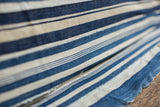 Handwoven texture with varied indigo blue and off-white stripes on the vintage throw.