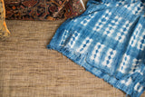 Hand woven vintage indigo throw with intricate white pattern and frayed edge.