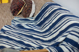 Supple hand-woven African indigo textile with wavy blue and cream stripes.