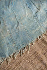 Close-up of vintage indigo throw, highlighting pieced construction, woven texture, and frayed fringe.