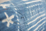Vintage indigo cotton throw with hand-woven texture, white abstract patterns, and visible wear.