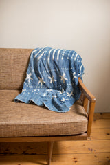 Draped vintage indigo throw with hand-dyed blue and white stripe and cross patterns.