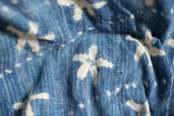 Vintage handwoven indigo blue textile, showing white flower-like resist-dyed patterns and stitching.