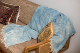 Hand-dyed vintage denim batik throw draped, highlighting varied indigo tones and fringe.