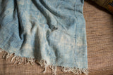 Fringed bottom edge of vintage hand-woven indigo cotton textile with varied blue texture.