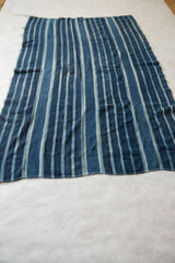 Hand-woven African indigo textile detail: textured blue stripes and natural variations.