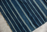 Close-up of vintage African indigo textile showing hand-woven texture, varied blue stripes, and storied stitching.
