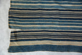 Vintage African indigo textile, hand-woven with varied blue and natural stripes and a split.