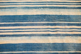 Hand-woven indigo striped textile, featuring varied blue and cream tones and natural texture.
