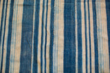 Handwoven indigo blue striped textile detail showcasing natural dye variations and intricate vertical stitching.