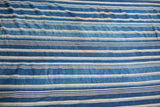 Hand-woven indigo blue striped textile with varying tones and textured weave.