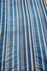 Handwoven vintage African indigo textile showcasing varied blue and off-white stripes and texture.
