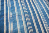 Close-up of handwoven indigo textile, with varying blue stripes and subtle storied repair.