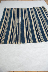 Hand-woven African indigo textile, with blue stripes and the aged character of its lower edge.