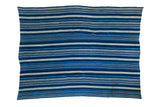 Vintage hand-woven indigo textile featuring diverse blue and light striped patterns.