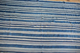 Angled view of handwoven indigo textile with varied blue and natural striped pattern.