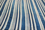 Detailed view of hand-woven vintage indigo textile with varied blue and cream stripes.