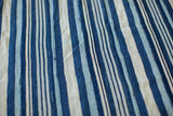 Vintage African indigo textile detail, handwoven with varied blue stripes and visible seams.