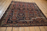 Angled view of an antique Malayer rug showing its rich tribal pattern and storied wear.