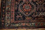 Corner detail of the antique Malayer rug showing a professionally secured mended split.