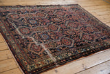 A professionally secured mended split across the dark geometric field of an antique Malayer rug.
