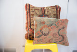 Late 18th century Turkish rug fragment pillow displaying faded blue, pink, and peach curvilinear motifs.