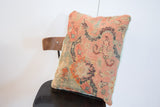 Lower corner of antique Turkish rug fragment pillow, with faded coral and blue motifs, light blue corduroy.