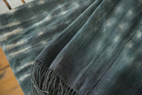 Hand-woven vintage African textile in indigo blue and ivory, showing texture and long tassels.