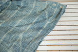 Hand woven African indigo textile with varied blue and ivory striped pattern.