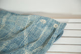 Close-up of hand-woven African indigo textile, showing denim, light blue, and ivory star patterns.