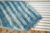 Hand-woven African indigo textile with varying blue and ivory stripes and fringed tassels.