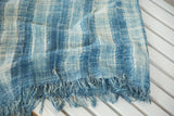Textured vintage African indigo textile, varied blue and ivory stripes with fringed edge.