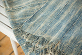 Vintage hand-woven African indigo textile featuring ivory and light blue patterns, fringed edge.