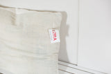 Pale indigo pillow texture with horizontal lines and small product tag.
