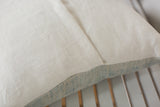 Ivory European linen pillow back featuring envelope closure and faded indigo edge.