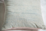 Textured sun-faded powder blue indigo pillow surface with subtle horizontal woven bands.