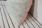 Faded powder blue indigo textile corner, showing woven texture and soft pink linen.