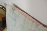 Edge detail of faded powder blue indigo pillow featuring pale pink linen.