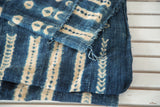 Folded vintage African indigo throw, showcasing intricate ivory patterns and hand-woven texture.