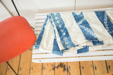 Folded African indigo throw showing hand-dyed blue stripes and resist-dyed circular motifs.