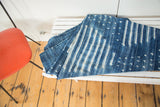Folded vintage African indigo textile throw, hand-woven with intricate ivory and denim patterns.