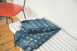 Intricate ivory geometric patterns on a folded, hand dyed African indigo textile.