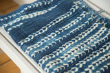 Close-up of hand-woven vintage African indigo textile with light blue and ivory patterns.
