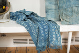 Collectible hand-woven indigo textile with ivory circle patterns and fringed edge.